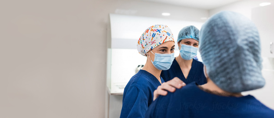 3 people standing in a group in scrubs, scrub caps, and marks