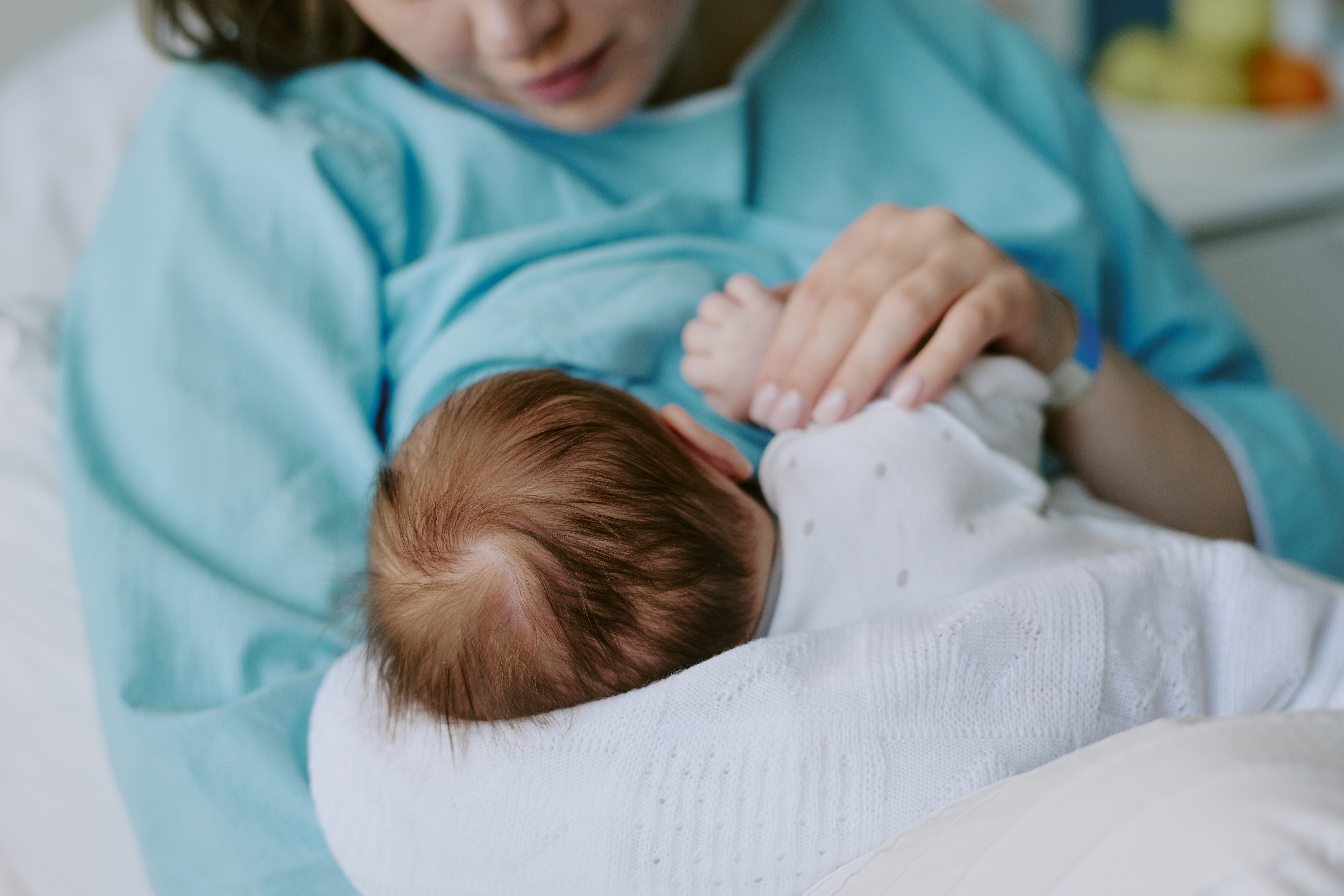 Mother holding her newborn baby in a hospital room.